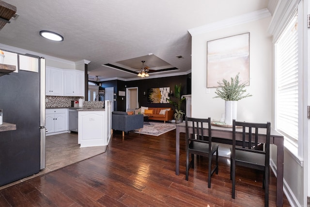 dining room featuring ceiling fan, dark hardwood / wood-style flooring, plenty of natural light, and a tray ceiling