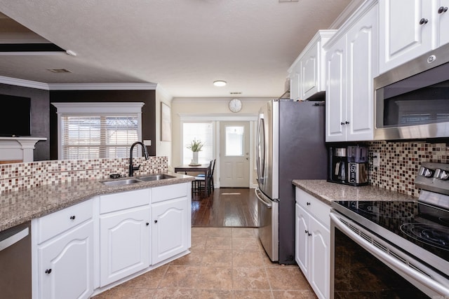 kitchen with tasteful backsplash, sink, white cabinetry, ornamental molding, and stainless steel appliances