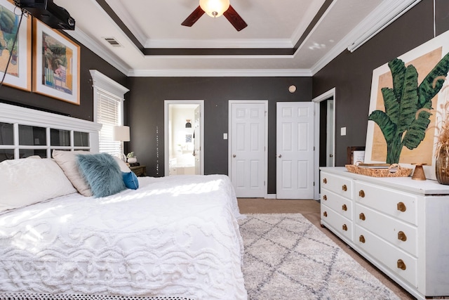 bedroom featuring ceiling fan, ornamental molding, connected bathroom, and a raised ceiling