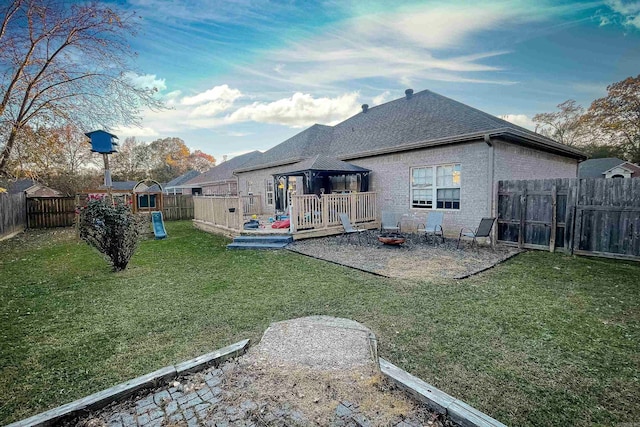 back of house featuring a gazebo, a fire pit, a yard, and a playground