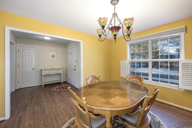 dining area with a textured ceiling, a chandelier, and dark hardwood / wood-style floors