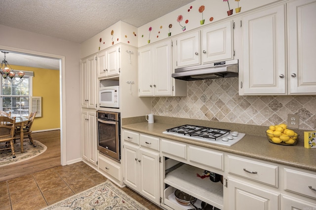 kitchen featuring light tile patterned floors, white appliances, white cabinets, and tasteful backsplash