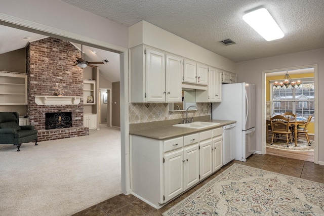 kitchen featuring sink, white cabinets, dishwasher, and a fireplace