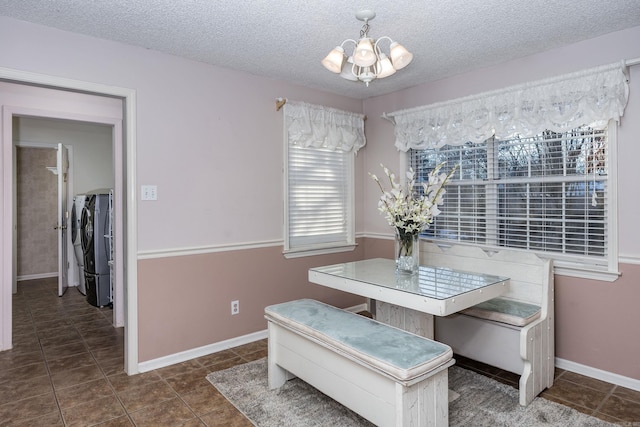 tiled dining space featuring washer and dryer, an inviting chandelier, and a textured ceiling