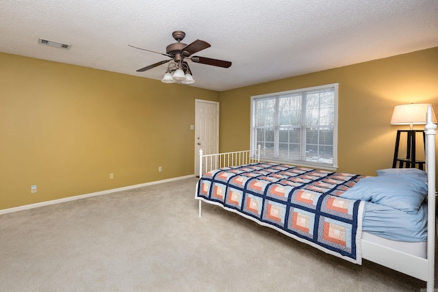 carpeted bedroom with ceiling fan and a textured ceiling