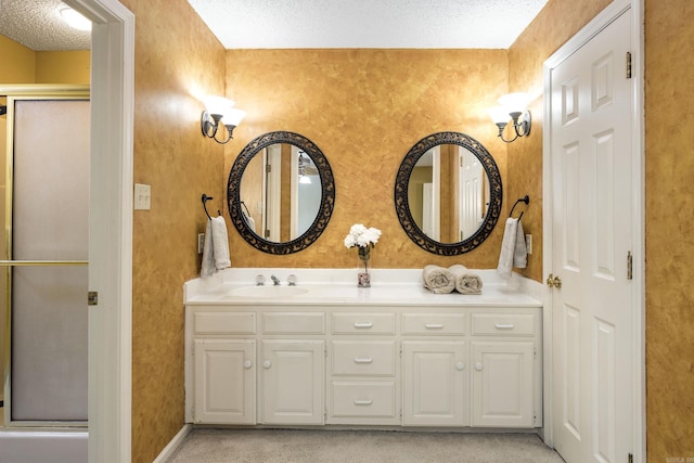 bathroom with vanity, a shower with door, and a textured ceiling