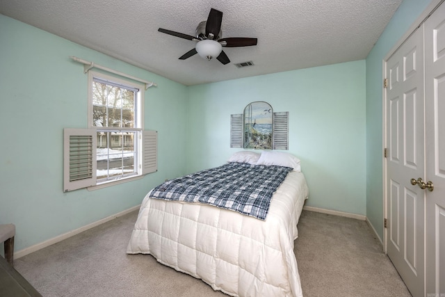 carpeted bedroom with ceiling fan, a textured ceiling, and a closet