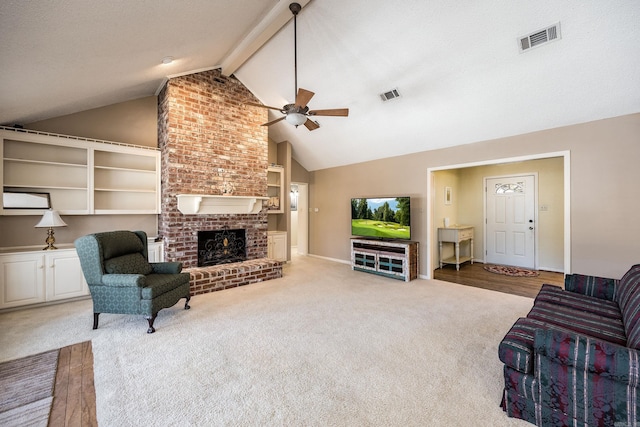 living room featuring ceiling fan, carpet floors, a fireplace, vaulted ceiling with beams, and a textured ceiling