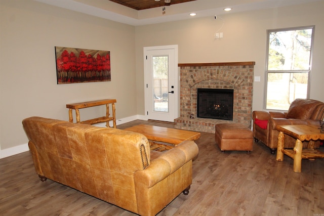 living room featuring a brick fireplace, a wealth of natural light, and wood-type flooring