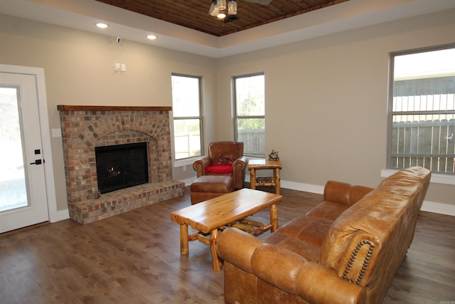 living room with wood ceiling, ceiling fan, a raised ceiling, dark wood-type flooring, and a fireplace