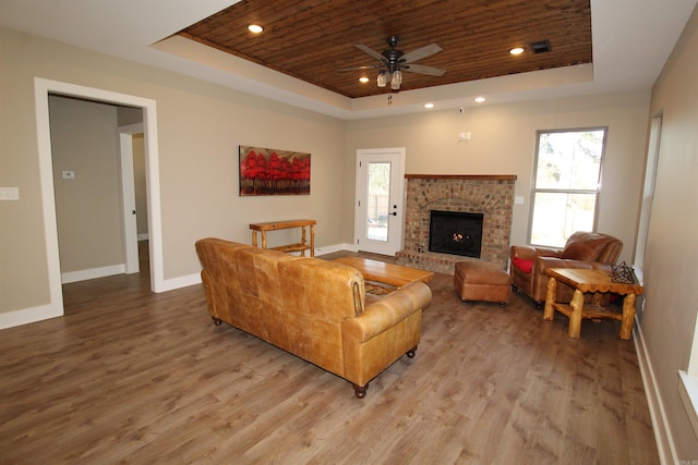 living room featuring ceiling fan, a tray ceiling, wood ceiling, and a fireplace