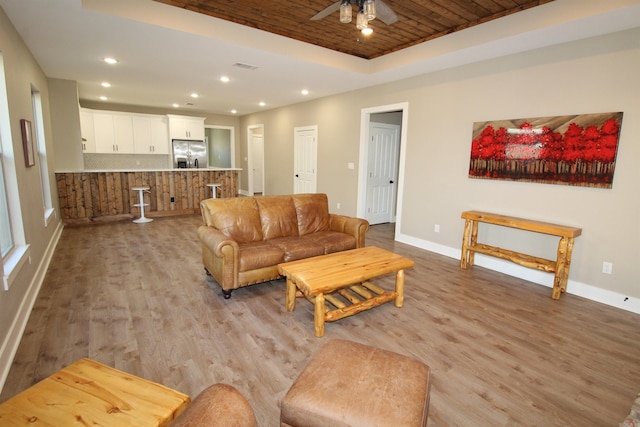 living room featuring ceiling fan, light hardwood / wood-style floors, a tray ceiling, and wood ceiling