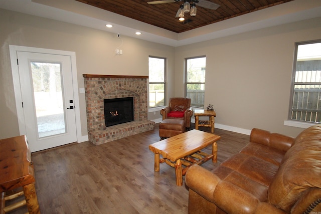 living room with wood-type flooring, a tray ceiling, wood ceiling, and a fireplace