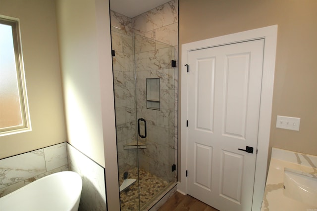 bathroom with hardwood / wood-style flooring, sink, and shower with separate bathtub