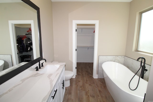 bathroom featuring a tub, hardwood / wood-style flooring, vanity, and toilet