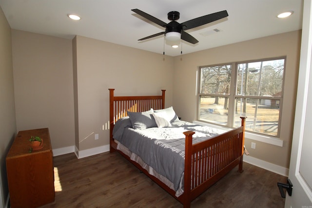 bedroom featuring ceiling fan, dark wood-type flooring, and multiple windows