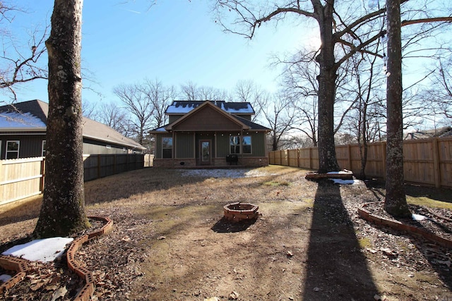 back of house featuring board and batten siding, an outdoor fire pit, and a fenced backyard