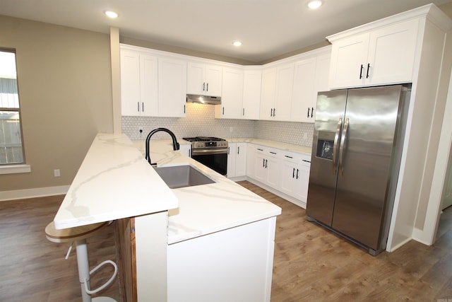 kitchen featuring kitchen peninsula, sink, stainless steel appliances, and white cabinetry