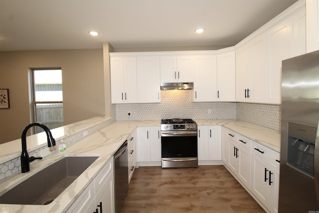 kitchen with decorative backsplash, sink, stainless steel appliances, white cabinets, and light stone counters