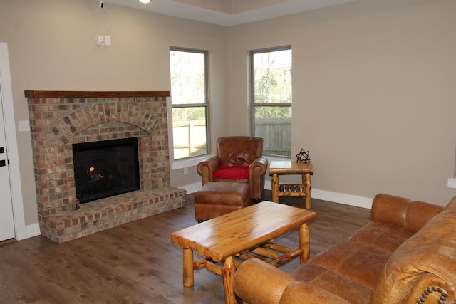 living room featuring a brick fireplace and dark hardwood / wood-style flooring