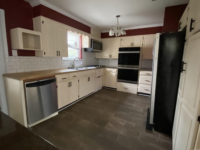 kitchen with appliances with stainless steel finishes, an inviting chandelier, decorative backsplash, sink, and hanging light fixtures