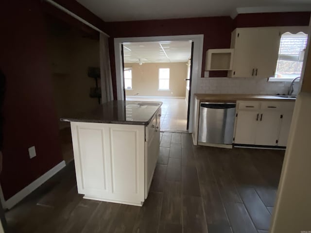 kitchen with white cabinets, a center island, dark wood-type flooring, decorative backsplash, and stainless steel dishwasher