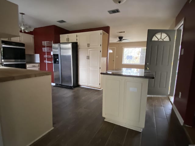 kitchen with ceiling fan, double wall oven, stainless steel refrigerator with ice dispenser, white cabinetry, and dark wood-type flooring