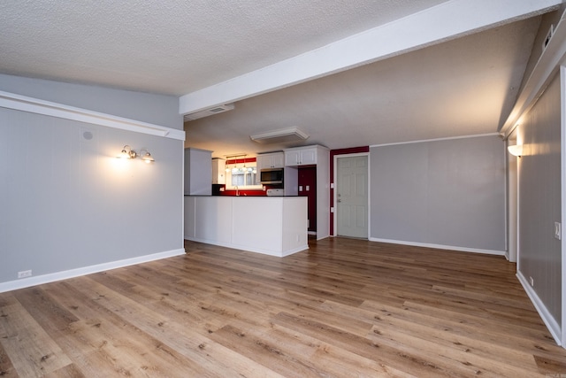 unfurnished living room with a textured ceiling, light hardwood / wood-style flooring, and lofted ceiling with beams