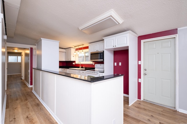 kitchen featuring light hardwood / wood-style floors, kitchen peninsula, white range with electric stovetop, white cabinets, and sink