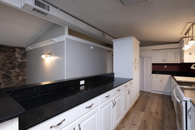 kitchen featuring lofted ceiling, pendant lighting, electric range, sink, and white cabinets