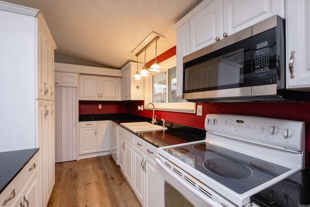 kitchen featuring lofted ceiling, sink, white appliances, a textured ceiling, and white cabinets