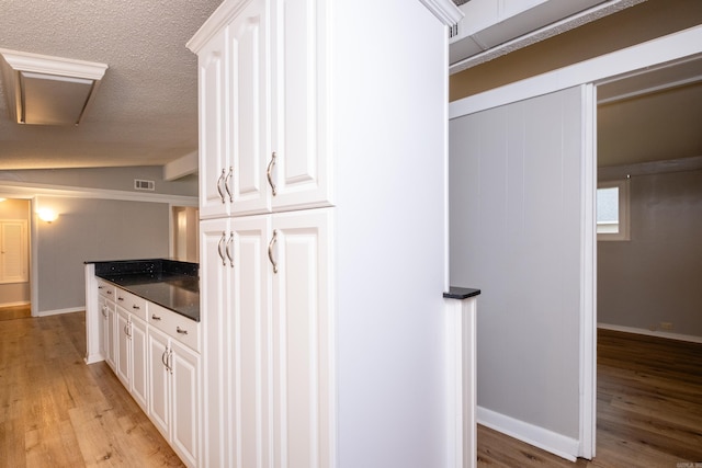 kitchen featuring lofted ceiling, white cabinetry, and light hardwood / wood-style floors