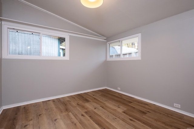 spare room featuring wood-type flooring and lofted ceiling