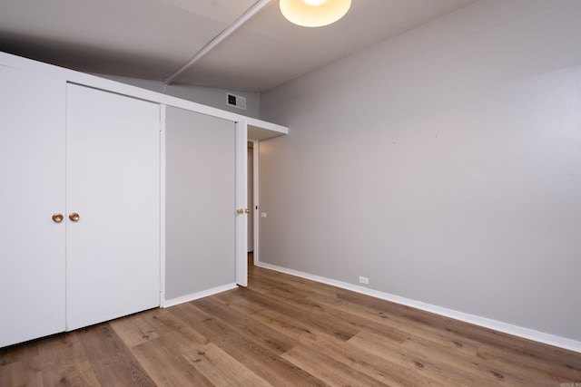 unfurnished bedroom with light hardwood / wood-style floors, a closet, and vaulted ceiling