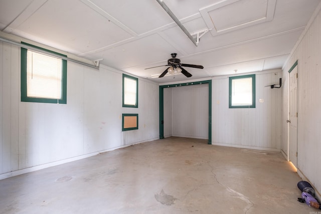 interior space featuring ceiling fan and wood walls