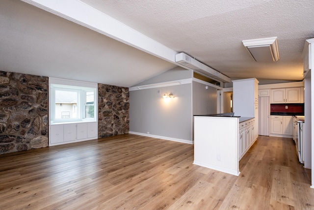 kitchen with white cabinetry, vaulted ceiling with beams, and light wood-type flooring