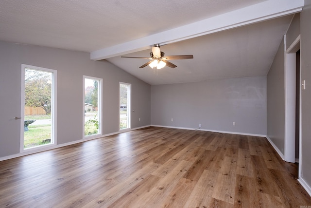 empty room with ceiling fan, vaulted ceiling with beams, a textured ceiling, and light hardwood / wood-style floors