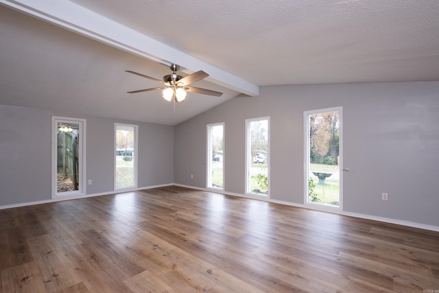 empty room featuring ceiling fan, vaulted ceiling with beams, a textured ceiling, and light hardwood / wood-style floors