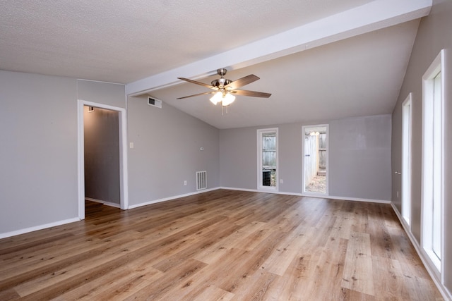 empty room with ceiling fan, lofted ceiling with beams, plenty of natural light, and light hardwood / wood-style flooring