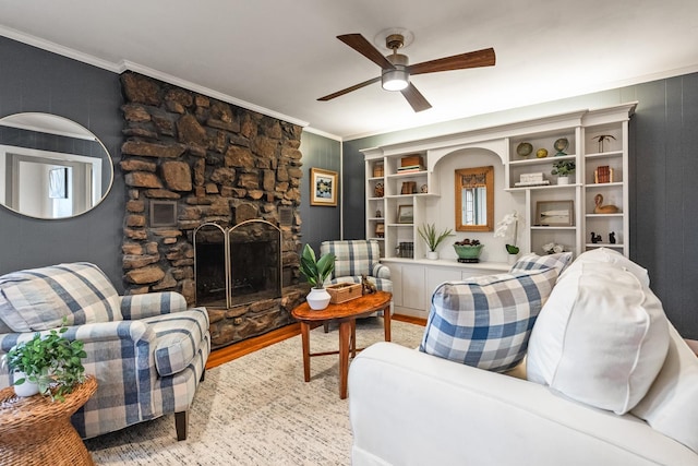 living room with ceiling fan, a fireplace, crown molding, and light hardwood / wood-style floors