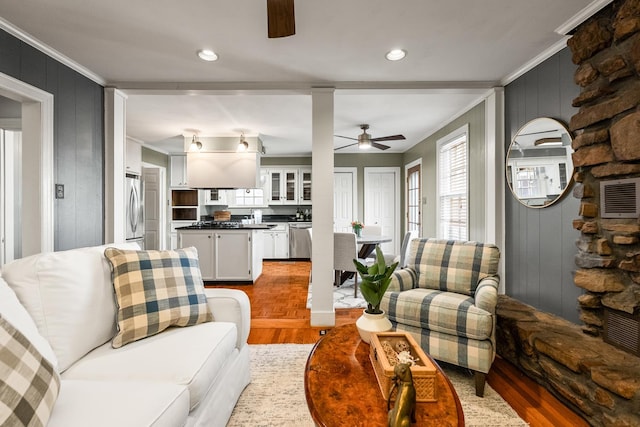 living room with ceiling fan, sink, wood-type flooring, and crown molding