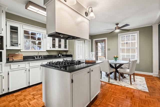 kitchen with white cabinetry, ceiling fan, black gas cooktop, a kitchen island, and sink