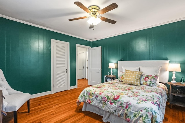 bedroom with ceiling fan, a closet, ornamental molding, and hardwood / wood-style floors