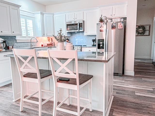 kitchen with stainless steel appliances, a kitchen bar, a center island, and white cabinets