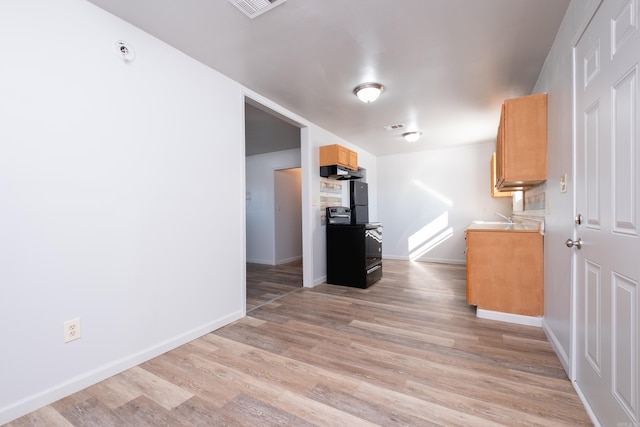 kitchen with electric range, sink, and light hardwood / wood-style flooring