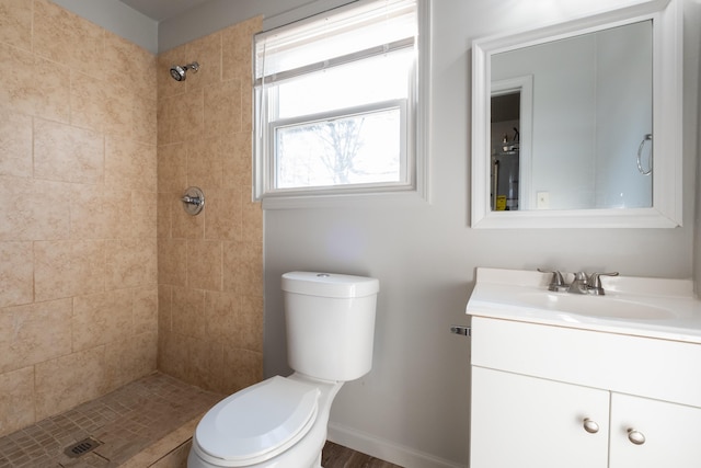 bathroom featuring toilet, vanity, and tiled shower