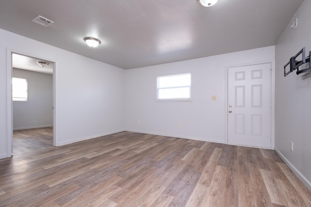 empty room with a wealth of natural light and light hardwood / wood-style floors