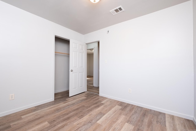 unfurnished bedroom with a closet and light hardwood / wood-style floors