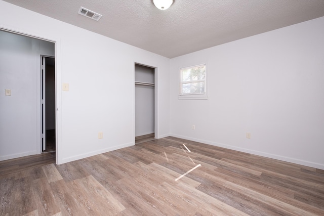 unfurnished bedroom with a textured ceiling, a closet, and light wood-type flooring