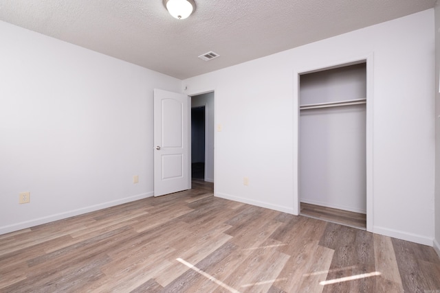 unfurnished bedroom with a textured ceiling, a closet, and light wood-type flooring